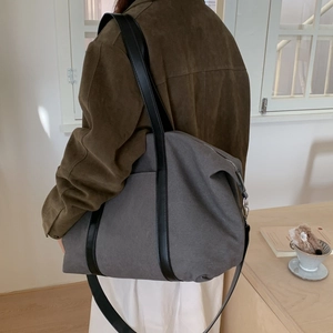 Vue détaillée du grand sac fourre-tout en toile grise porté à l'épaule par un mannequin