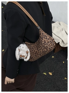 Detail einer Hobo-Tasche mit Leopardenmuster, Plüsch-Hasen-Anhänger und Lederriemen