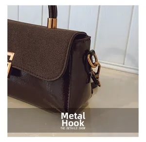 Detail der dunkelbraunen Handtasche mit goldenem Haken und gemischten Texturen
