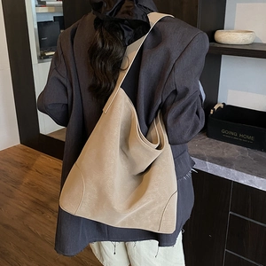 Rear view of a model wearing the large beige hobo bag with wide shoulder strap details