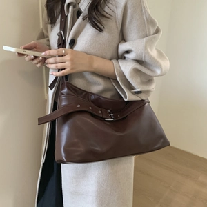 Detail view of a vintage dark brown leather tote bag with stylish metal buckle straps