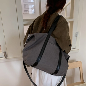 Détail du grand sac cabas en toile gris foncé avec bandoulière en cuir noir sur un modèle