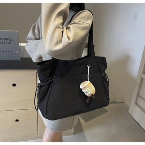 Vue détaillée d'un grand sac cabas noir avec cordon et pendentif en peluche mignon