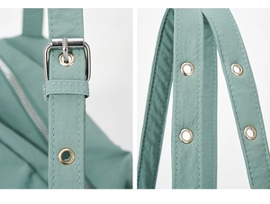 Detail of adjustable shoulder strap with silver metal grommets on a light green bag