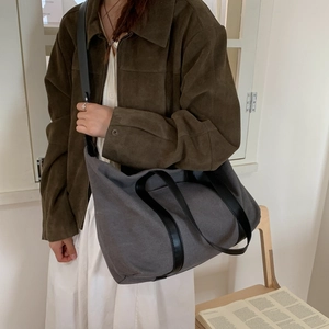 Détail du grand sac cabas en toile gris foncé avec lanières en cuir PU porté par un modèle