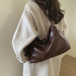 Detail view of deep brown leather tote bag showing wide strap and silver metal buckle