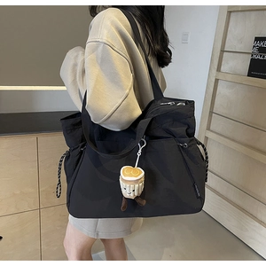 Détail du sac fourre-tout noir avec cordon de serrage et breloque peluche tasse à café