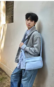 Lightweight light blue nylon crossbody bag shown in use against a textured grey wall