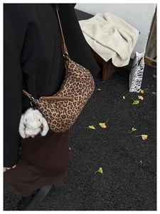 Detail of leopard print crescent bag with leather strap and plush bunny charm on street