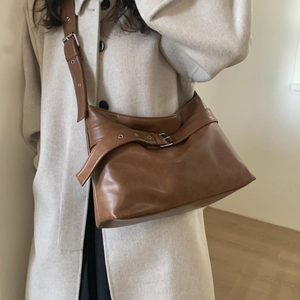 Detail of a brown vintage tote bag with cross-belt buckle and adjustable wide strap