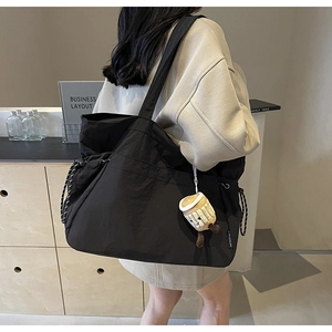 Détail d'un grand sac fourre-tout en nylon noir avec cordon et breloque tasse à café