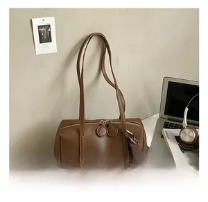 Detailed close-up of brown oiled leather shoulder bag with chocolate charm on a desk