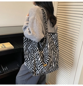 Detail view of large zebra pattern tote bag with plush fabric and gold metal plaque