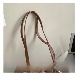 Close-up of brown faux leather shoulder bag handles and sturdy metal zipper detail