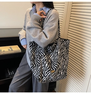 Detail of zebra-print tote bag with gold logo plaque shown in lifestyle setting