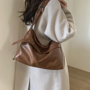 Detailed side view of a large brown leather tote bag with stylish metal eyelet strap buckle
