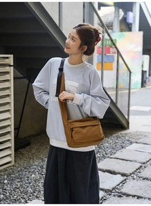 Detailed shot of brown nylon messenger bag with wide black strap and front pocket