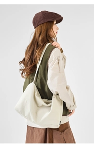 Side view of model wearing a beige canvas crossbody bag with drawstring details