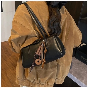 Detail of black leather Boston bag with unique chocolate and donut charms on the side
