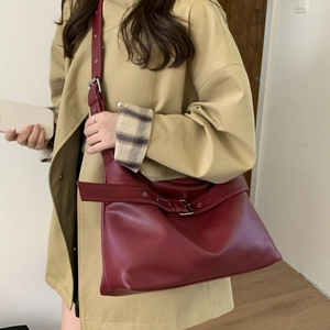 Close-up of vintage burgundy tote bag with silver buckle and adjustable shoulder strap