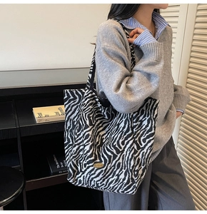 Detail of zebra print tote bag featuring a metal handmade tag and soft knit texture