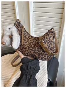 Detail der hobo-tasche mit leopard-print, braunem lederriemen und grauem hasen-anhänger