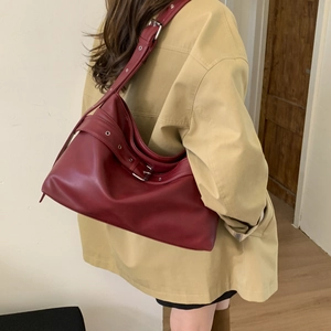 Detail of burgundy tote bag with silver metal eyelets and adjustable strap on model