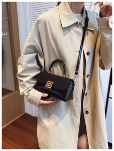 Detailansicht der schwarzen Ledertasche mit goldener Schnalle zum beigen Trenchcoat