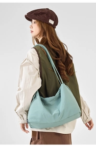 Detail view of large light blue pleated nylon tote bag worn by model in casual style
