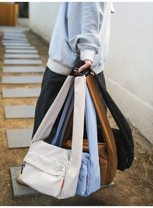 Group shot of colorful nylon messenger bags showing off-white, blue, brown, and black options