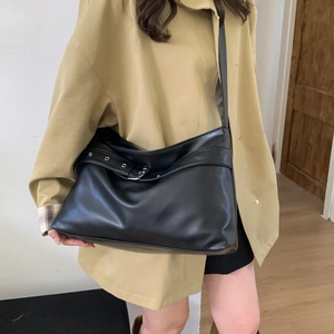 Detail of black leather tote bag with adjustable strap worn with a khaki trench coat