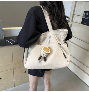 Détail macro du sac fourre-tout beige montrant l'étiquette CHUANGMI et le charme