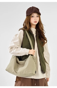 Detail of light khaki pleated drawstring crossbody bag styled with an olive green vest
