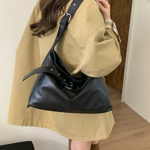 Detail of minimalist black oversized tote bag with adjustable strap worn by model