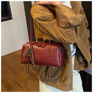 Detail view of burgundy leather Boston bag with vintage texture and chocolate charm