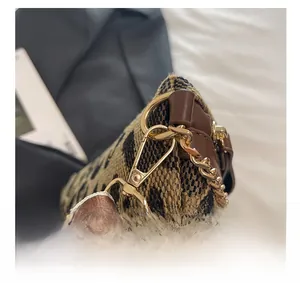 Close-up of golden hardware clasp with leopard print fabric and striped strap