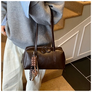 Detail of dark brown vintage shoulder bag with large circular zippers and charm