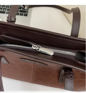 Detailed view of silver metal zipper and brown lychee grain leather on tote bag