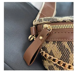 Close-up of brown tweed woven fabric with leather trim and gold metal chain strap detail