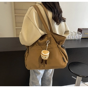 Détail du sac cabas en toile caramel avec étiquette de marque et pendentif gâteau