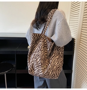 Detail of zebra print tote bag featuring a high-quality handmade metal logo plaque