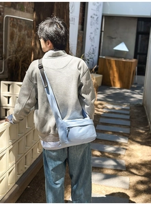 Adjustable wide strap on a light blue nylon crossbody bag shown in outdoor use