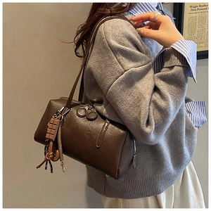 Detail of vintage oil-wax leather shoulder bag with a chocolate bar pendant and tassels