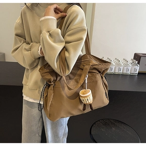 Détail d'un grand sac cabas marron en nylon avec bandoulière et breloque tasse de café