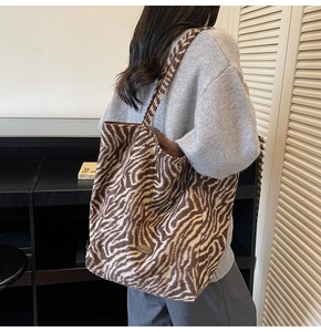 Detail of a large brown and white animal print tote bag with a handmade metal tag