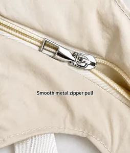 Dettaglio della cerniera in metallo argentato liscio su una borsa tote beige