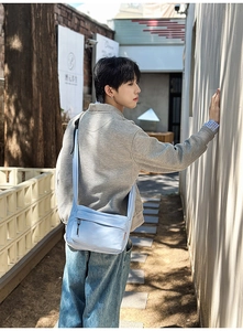 Detail of light blue nylon crossbody bag with multi-zippered pockets for city style