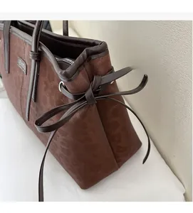 Detail of a dark brown leopard print tote bag with a decorative side leather bow