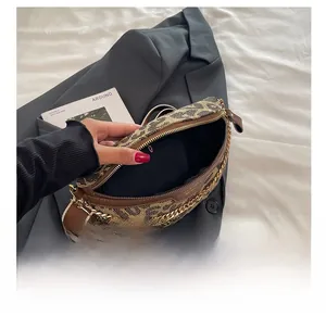 Detail showing internal compartment of leopard print chest bag with gold chain and canvas texture