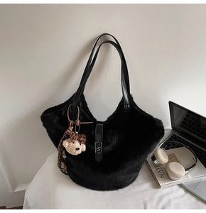 Détail du sac fourre-tout noir en fausse fourrure avec bandoulière en cuir et breloque ours